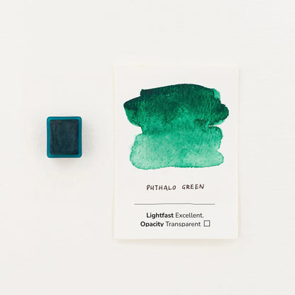 A watercolor paint swatch card labeled 'PHTHALO GREEN' with a green wash on white paper, shown next to a watercolour half pan on a clean white background.