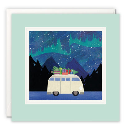 Campervan with a Christmas tree and presents on the roof under green northern lights