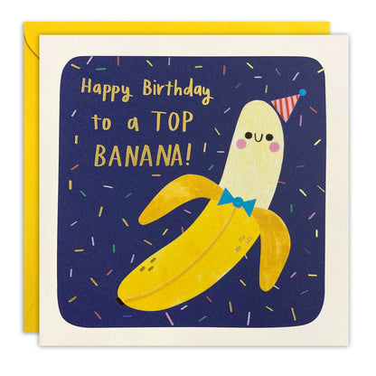 Square birthday card of a smiling banana with bow tie on navy, gold foil 'Happy Birthday to a Top Banana!'
