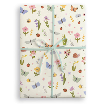 Cream wrapping paper with butterflies, bees, ladybirds and wild flowers, tied with a pale blue ribbon